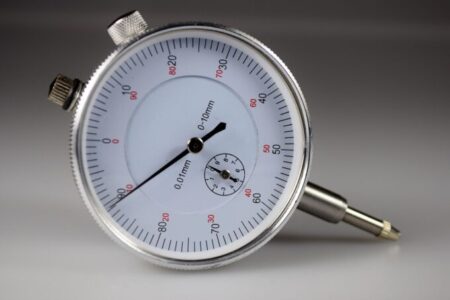 Close-up of a dial indicator with 0.01 mm graduations against a grey background.
